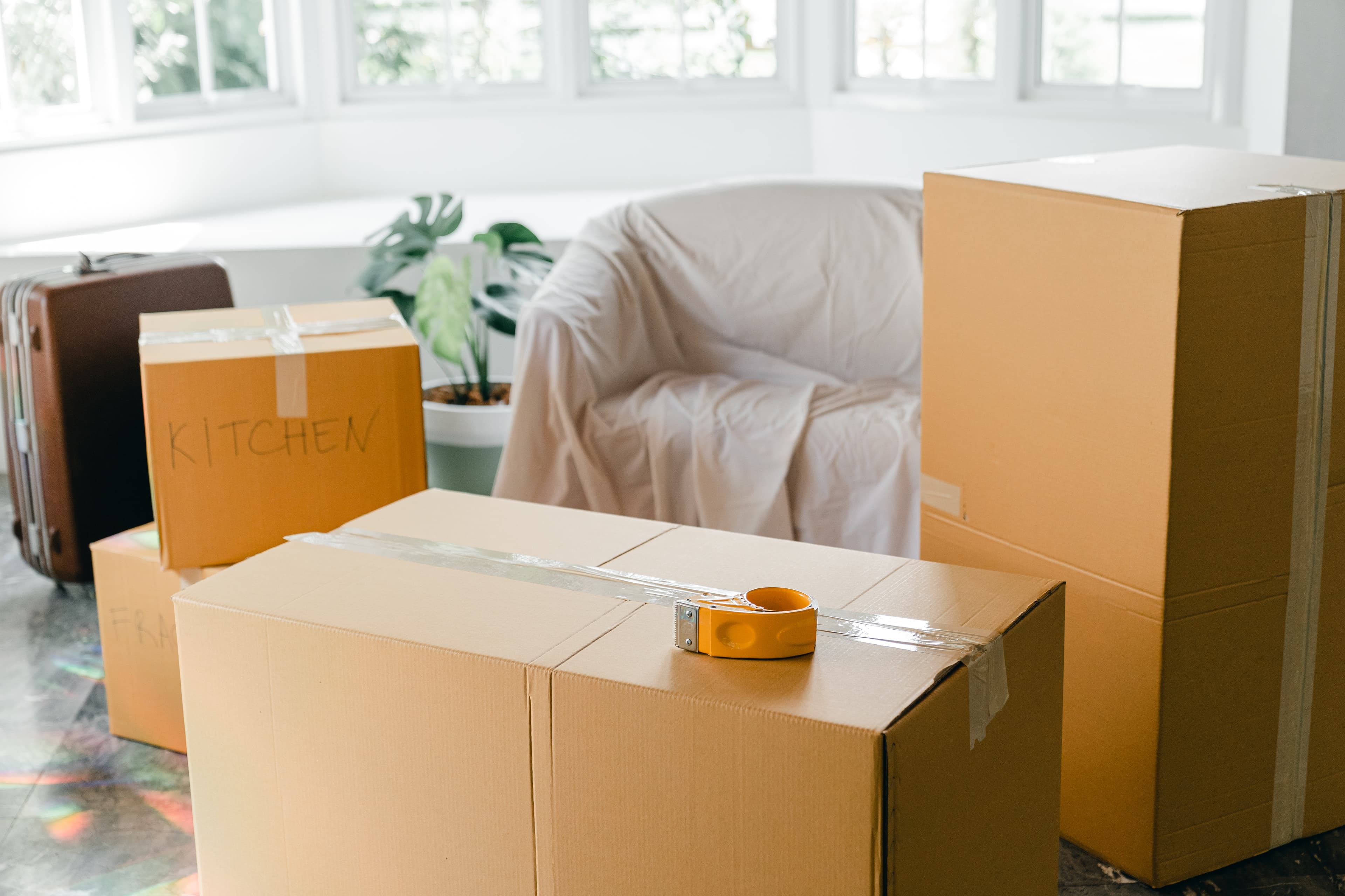 Moving boxes and a couch covered in a sheet in preparation for moving.