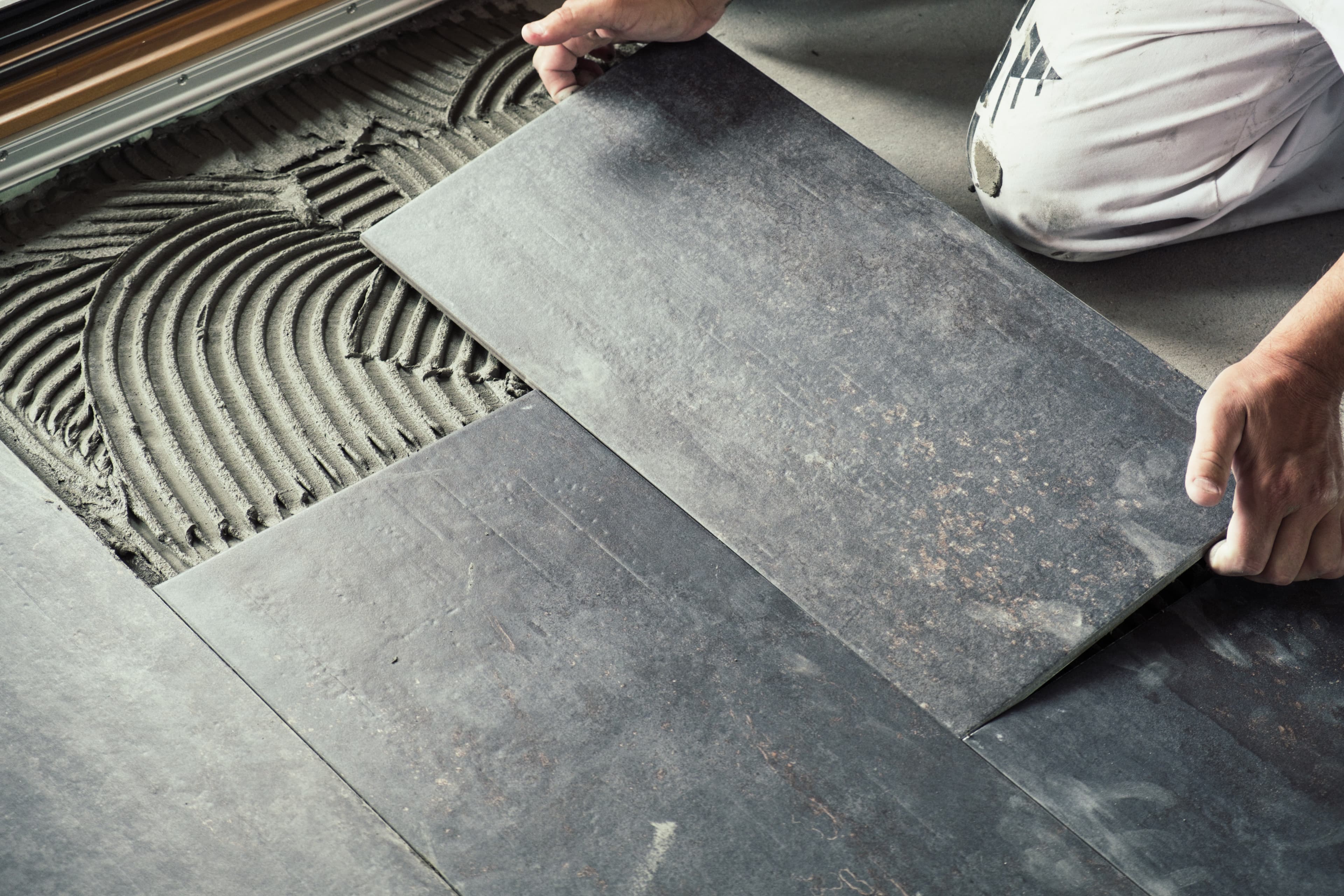 Dark gray tile flooring being installed